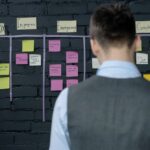 man-in-suit-vest-standing-near-black-wall-with-sticky-notes